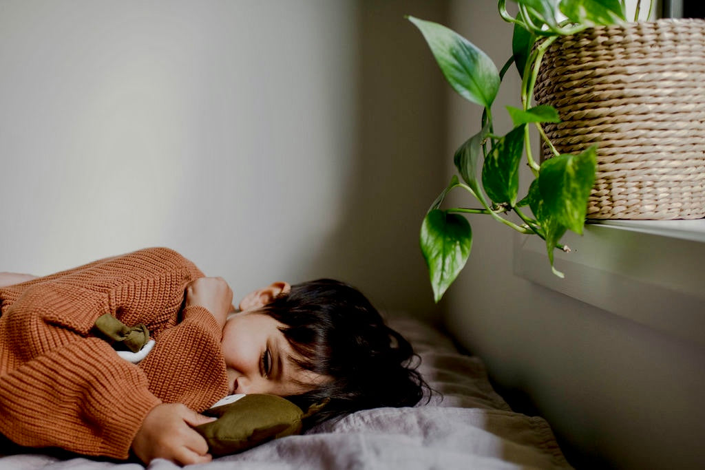 Smiling child laying on a bed with a Little Koko Bear comforter