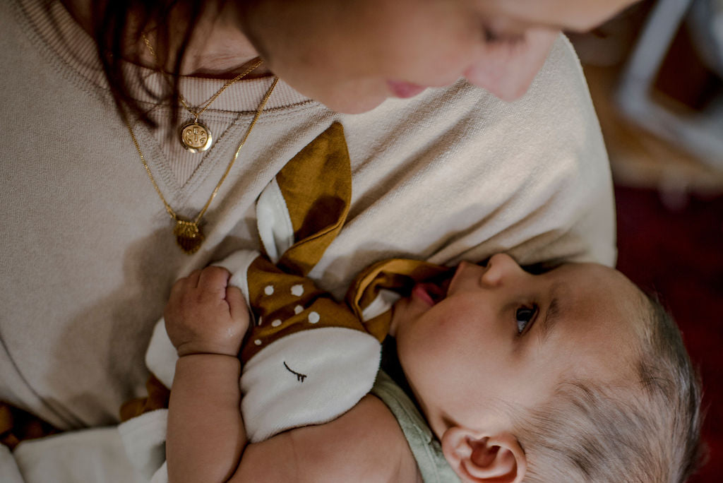 An engaged mother with her content baby, looking into each others eyes with a Little Koko Lullaby Deer Comforter