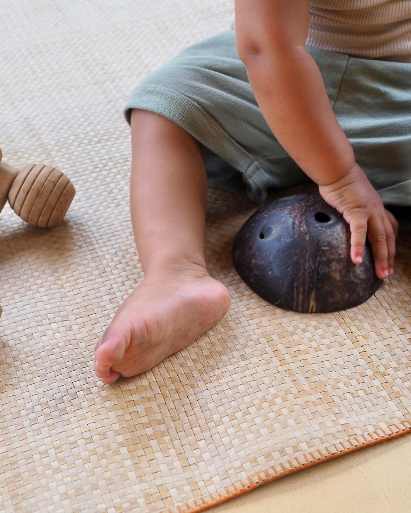 Natural play mat with a baby playing with coconut shells, woven, perfect for yoga or baby