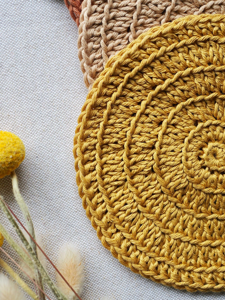 a mustard crochet 100% organic cotton little koko wash cloth and a billy button daisy