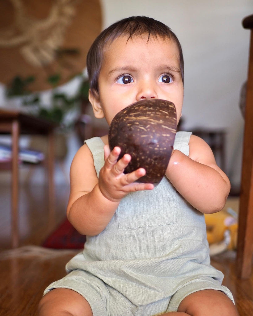 a baby playing with a little koko bath time coconut shell 