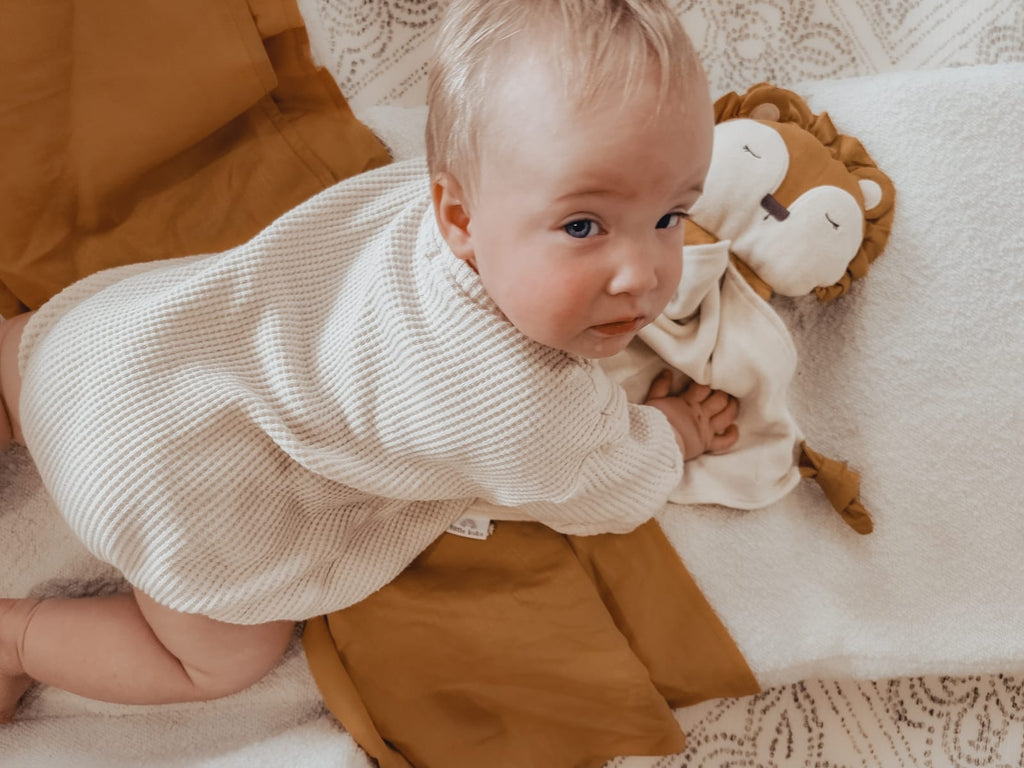 a little girl with her little koko lion comforter on a play mat